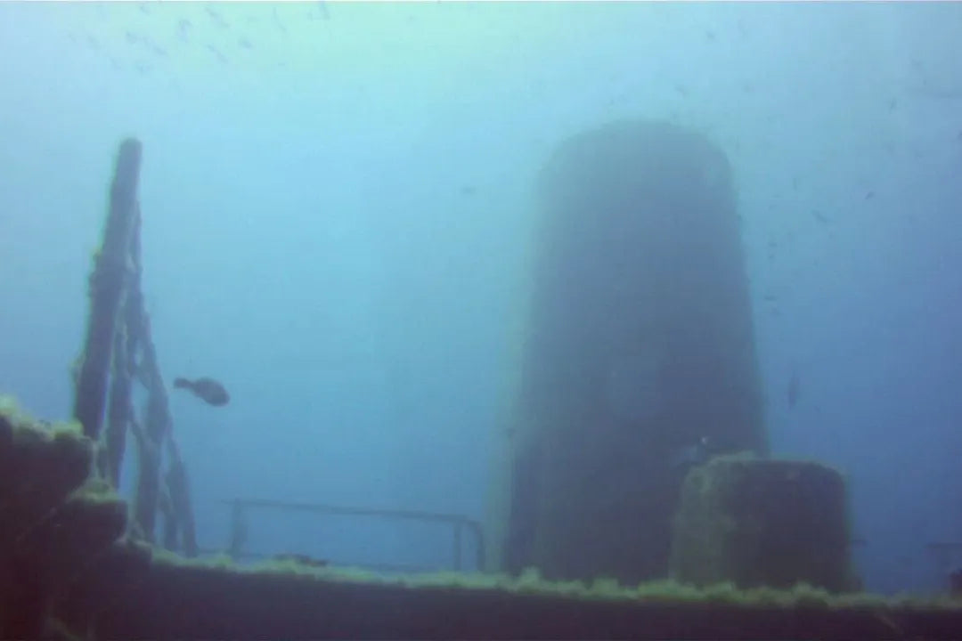 Funnel and bridge structure of the Um El Faroud in murky blue, with the deck railing in front