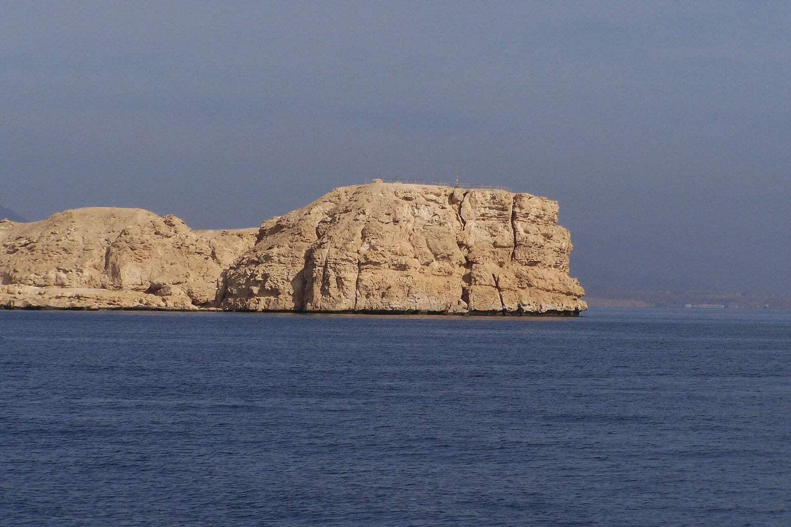 Bright limestone cliffs above the dark blue, calm sea